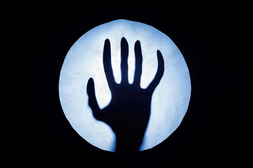 Alien hand behind a blue matte glass. Blurry hand abstraction. Round window. Horror concept. Copy space...