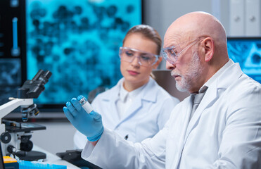 Professor and doctor work in a modern scientific laboratory using equipment and computertechnologies. Group of scientists make research and develop new vaccines. Science and healthcare concept.
