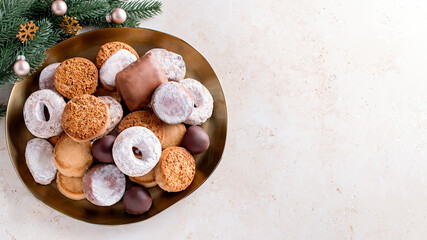 Fototapeta na wymiar Holiday delicacies polvorones and mantecados in golden plate on beige stone table overhead