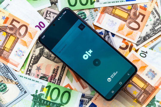 smartphone screen with online marketplace OLX application on US dollar and euro banknotes background