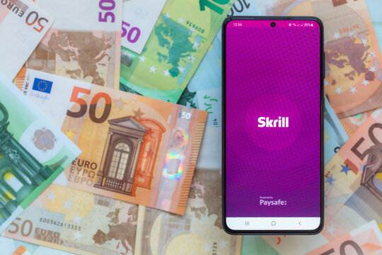 smartphone screen with digital payment service Skrill mobile application on euro banknotes background