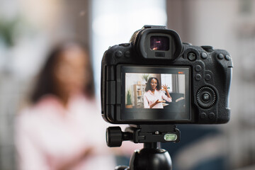Blur background of african american woman in eyeglasses and pink shirt recording new video blog for...