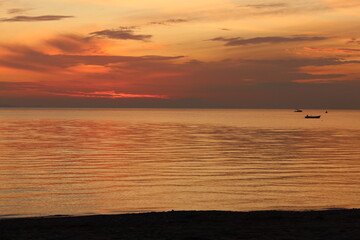 Sunset on a beach with silhouettes of boat and mytilene island. Calm water and sweet colors compose a nice picture. Taken in akcay edremit aegean sea coast turkey anatolia asia at the end of the day.