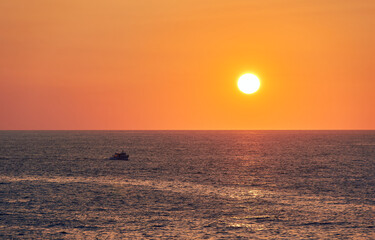 paisaje de un barco pesquero navegando bajo el sol del atardecer