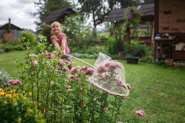 Happy preteen girl catching a butterfly in the village garden at summer, happy summertime, young...