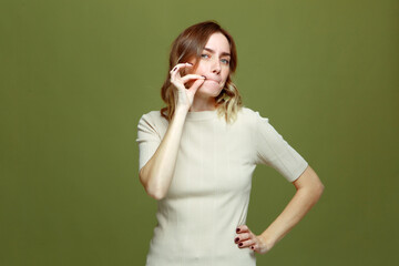 Serious trustworthy young girl promise to be quiet and keep secret, showing silence gesture on...