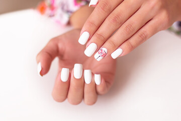 Naklejka premium Close up view of beautiful female hands with romantic manicure nails, pink and white gel polish, peonies flowers design