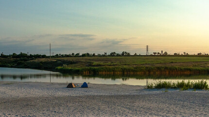 two tents in the beach . Lake and morning . Camping on the beach . Sunrise over the lake . 