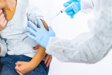 Fototapeta premium A female doctor calming the child with his mother before the vaccine injection. Vaccination of children. Immunization in the coronavirus pandemic, covid-19