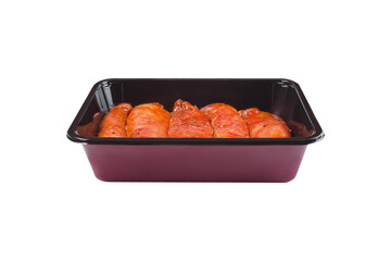 Fresh marinated chicken meat.Raw marinated chicken fillet in red sauce in a tray for a supermarket, in a roasting tray on a white isolated background, copy space. Oven ready chicken.