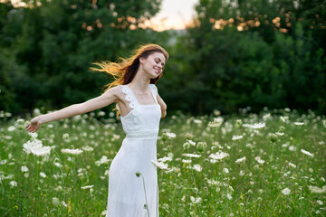 cheerful woman in a field with flowers in a white dress in nature