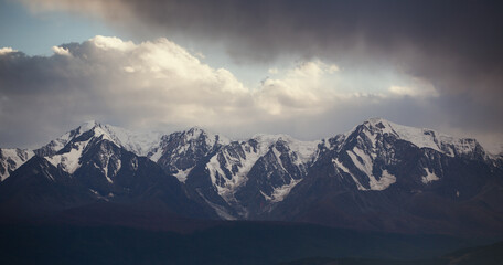 Gloomy autumn snow-capped mountains and cloudy sky.