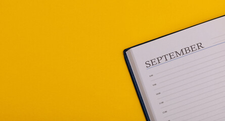 Notepad or diary on a yellow background. Calendar for September. Fall time. Space for text, long size