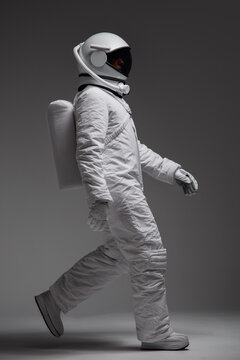 Studio portrait of a walking astronaut. Gray background.