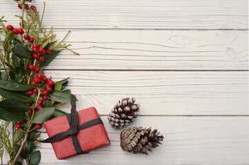Bittersweet Box Wrapped in Red Kraft Paper and Green Ribbon with Two Pinecones in Lower Right-Hand Corner of White Paneling with Room for Text