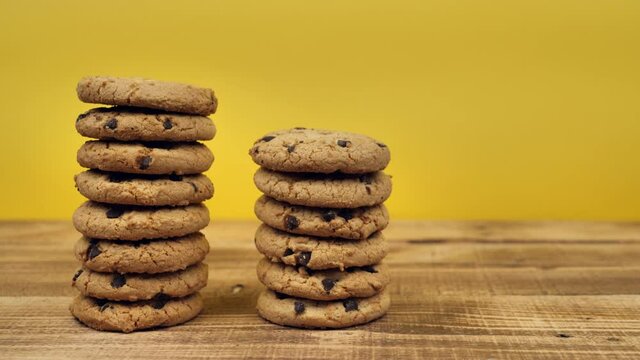 three stacks of chocolate oatmeal cookies trim on a wooden table with a yellow background