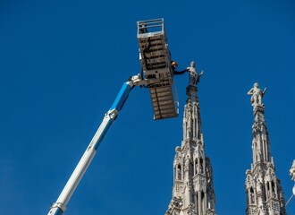 Technicians on lifting platform for scheduled maintenance plan and study of the degradation phenomena of the Milan cathedral