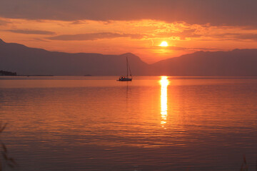 Fototapeta na wymiar Scenic sunset and a lonely sailboat at the coast of Trogir