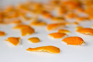 Defocus blurred Christmas background from the peels of orange and tangerine on a white background. Many small pieces of dried peel. Pattern. Isolated. Orange bright color. Mock-up. Out of focus