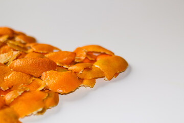 Defocus blurred Christmas background from the peels of orange and tangerine on a white background. Many small pieces of dried peel. Copy space. Orange bright color. Mock-up. Isolated. Out of focus