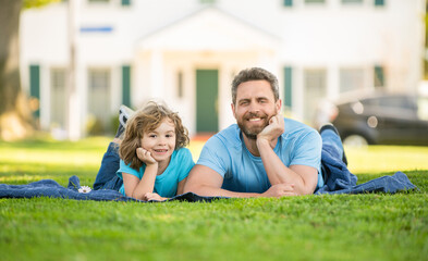 smiling father with kid relax together on green park grass, summer