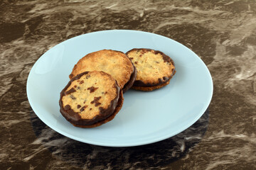 Three cocoa chocolate filled oat cookies on blue snack plate