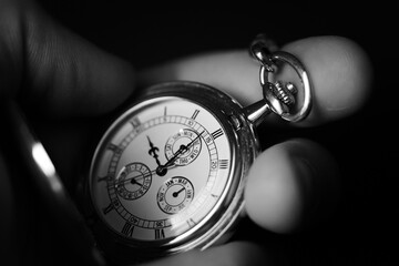 Obraz na płótnie Canvas Hand holding a luxury pocket watch. Extreme close up, black and white.