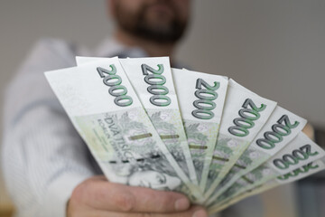 Czech koruna in nominal Two thousandth banknotes 2000 CZK. Men hold a fan of korun on hand. Czechia criminal cash credit