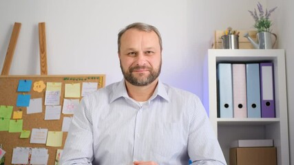 Middle aged man gestures hello at the camera, listens and nods his head. Make online call live video conference chat using a computer.