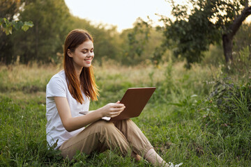 woman outdoors sitting on the grass with laptop summer vacation communication