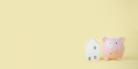 Piggybank and mini house on yellow background with copy space, prepare money for new house, family plan, home, loan, money investment concept....