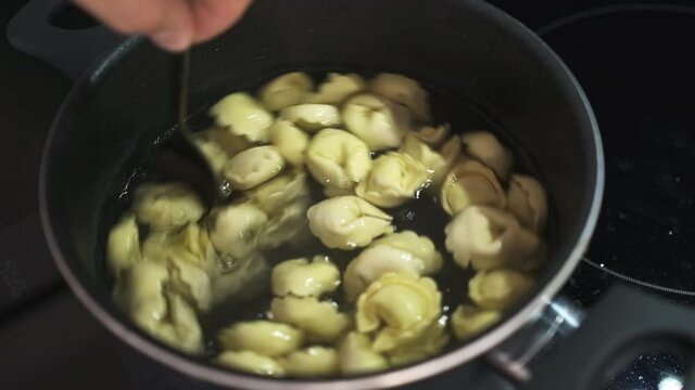 Person Stirs Tasty Ravioli In Saucepan With Boiling Water Standing On Stove Extreme Close View. Cooking Tasty Hearty Dinner For Family