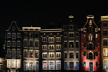 Famous houses in city of Amsterdam. Typical Dutch houses with colorful facades at night. Dancing houses in Netherlands. 