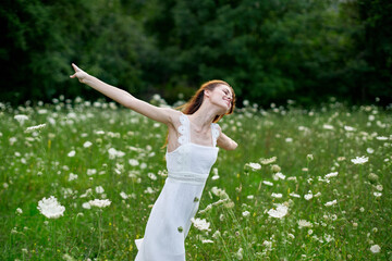 Obraz premium cheerful woman in a field with flowers in a white dress in nature