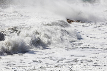 big waves breaking on the shore, with white foam