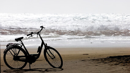 Obraz premium Abandoned bicycle on the sand, strong sea bottom and big waves.