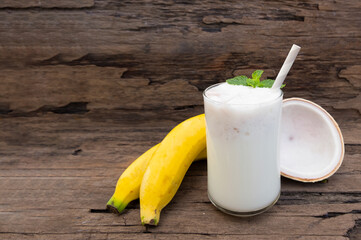 Coconut blend banana milk smoothie drink fresh cocktail shake milkshake vanilla juice fruit beverage food healthy the taste yummy In glass on wooden background.
