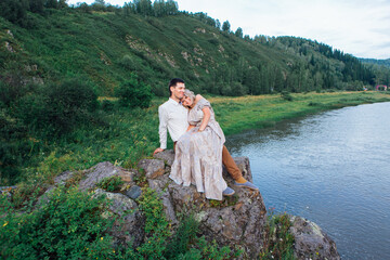 Romantic inloved couple sitting on rocks by the river.