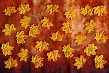 brown background with fallen bright yellow-red autumn artificial maple leaves