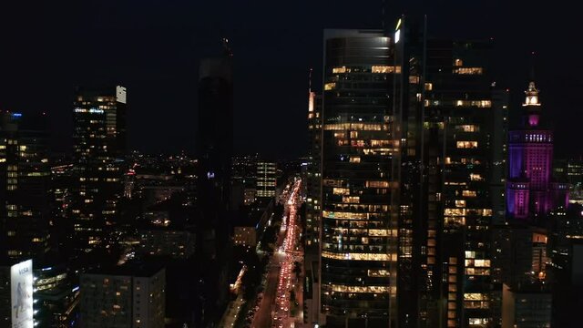 Forwards fly around downtown skyscrapers at night. Traffic jam in street bellow. Endless stream of car lights. Warsaw, Poland