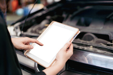 Asian young woman examining and using a digital tablet in vehicle repairing and diagnostic in garage. 