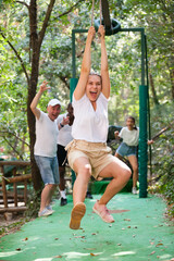 Fototapeta premium Excited men and women passing zipline in adventure park