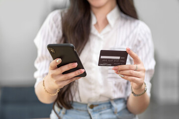 Close up. woman holding smartphone and using credit card for online shopping.