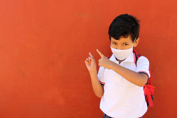 Latino boy with uniform shirt, backpack and mask back to school happy and excited about the new normal for the Covid-19 pandemic
