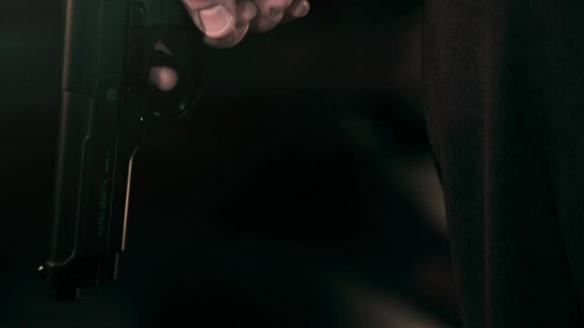 Close up on hands of secret agent man in suit holding a pistol, pan up cinematic