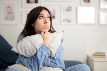 Stressed Woman Embracing Pillow Sitting in her Bad at Home