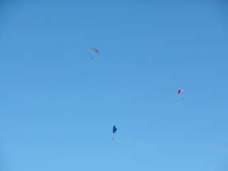 Naklejka na ściany i meble Three men parachute in the blue sky