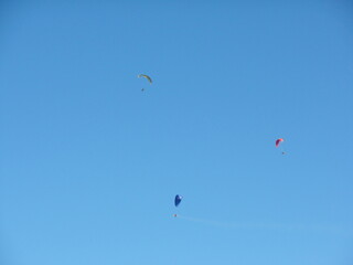 Three men parachute in the blue sky
