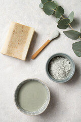 Organic cosmetic green clay, soap and eucalyptus branch on a white textured background. The concept of spa and wellness. Top view