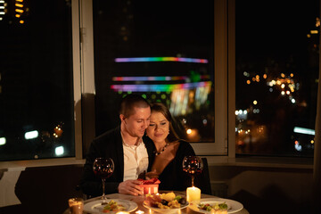 Valentine's day date with candles and wine, romantic dinner for two, man and woman in a restaurant at night by candlelight, married couple anniversary